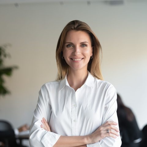 Smiling beautiful female professional manager standing with arms crossed looking at camera, happy confident business woman corporate leader boss ceo posing in office, headshot close up portrait