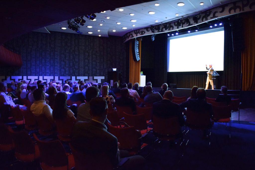 Event met zaal vol mensen en een spreker op het podium