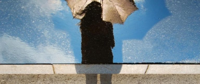 Kvinna i svarta kläder med ett paraply. Illustration av titeln på arikeln som heter innusion eller verklighet