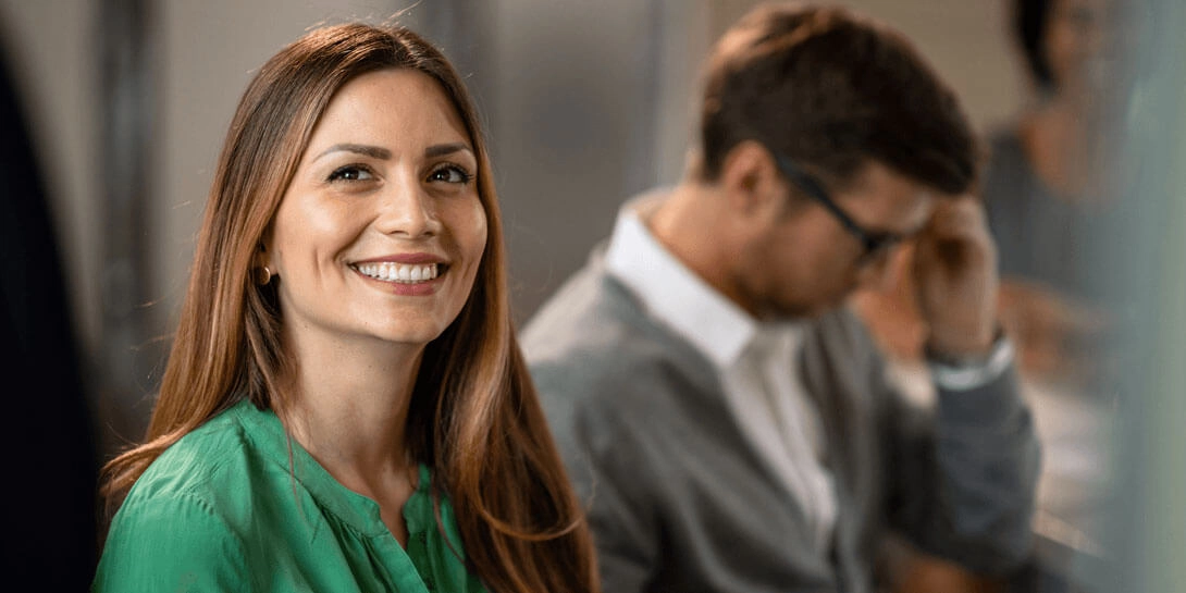 En kvinde i en grøn bluse sidder og smiler